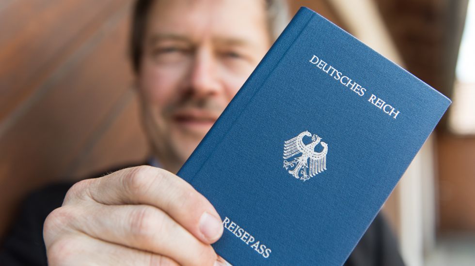 Ein Reichsbrüger hält seinen blauen Reisepass in die Kamera, auf dem steht: Deutsches Reich, Reisepass