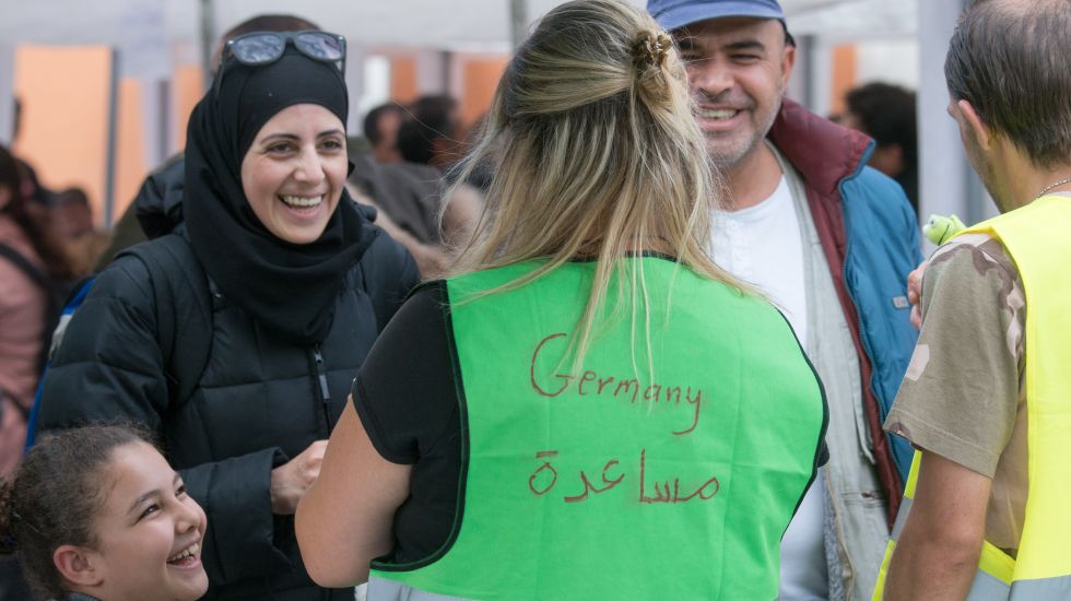 "Germany" steht am 19.09.2015 am Hauptbahnhof in Passau (Bayern) auf der Weste einer Helferin, die mit syrischen Flüchtlingen spricht.